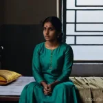 Home 11 범죄 피해자 가정 폭력 피해 신고 방법 - **Prompt:** A young woman, perhaps in her late 20s to early 30s, sitting alone on a simple cot in a ...